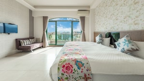 Une chambre d’hôtel avec un grand lit, un canapé, une télévision à écran plat et un balcon offrant une vue sur la ville.