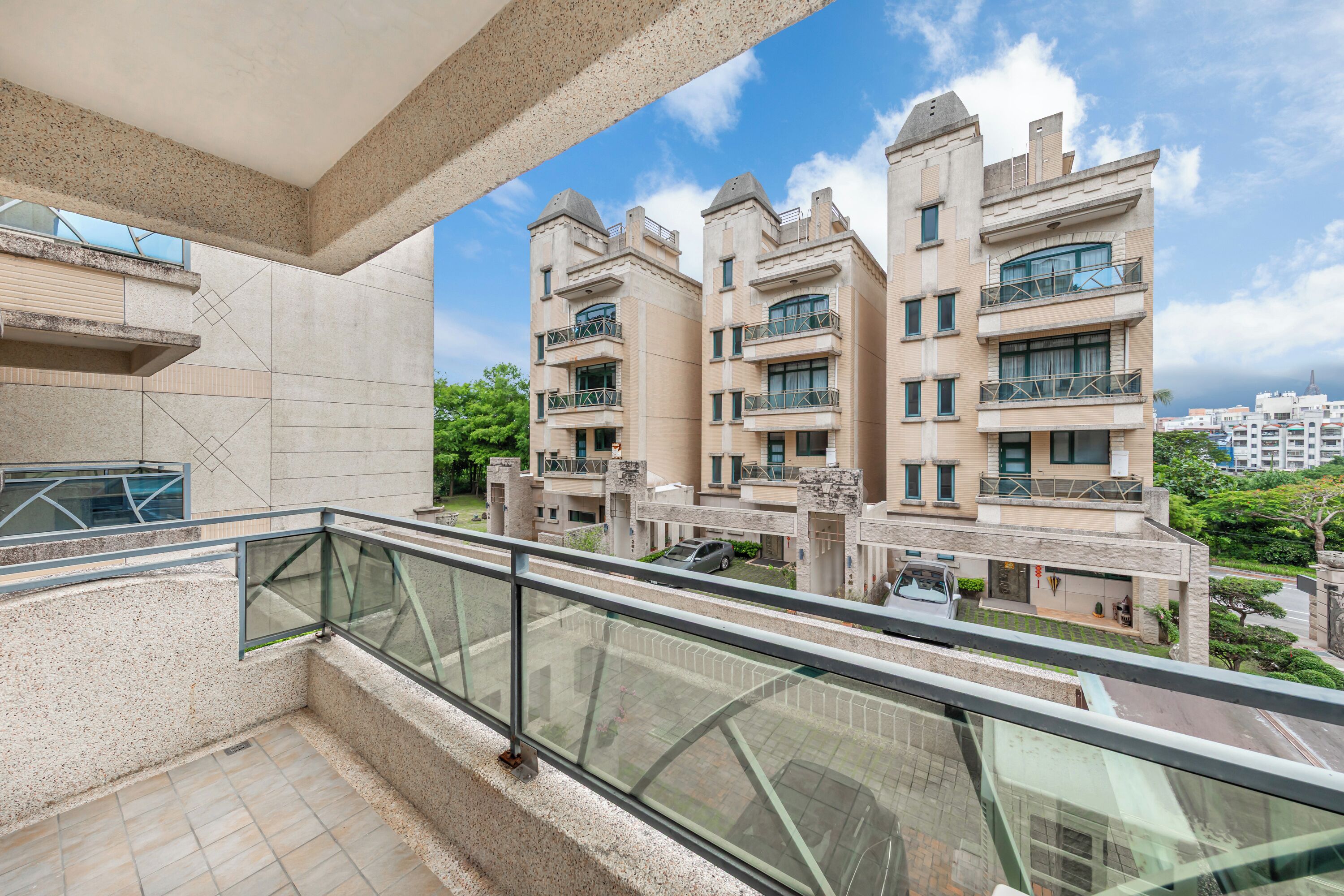 A modern apartment building with multiple balconies, large windows, and a clear view of the surrounding area.