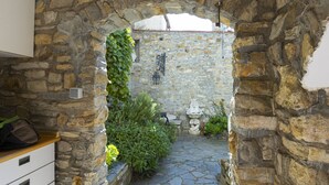 A stone archway leading to a courtyard with a stone wall, a lantern, and a statue. - Typical Ligurian house with garden and sea view terrace (Cipressa)