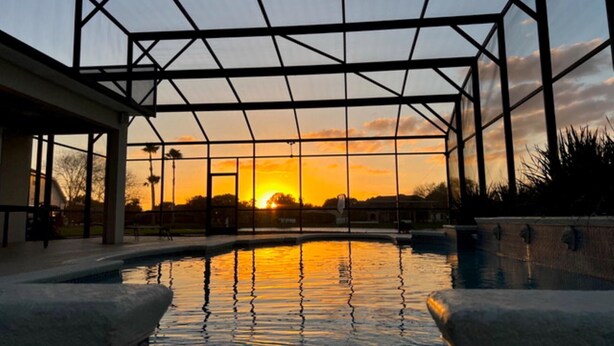 Piscina con vista sul tramonto, circondata da una struttura in metallo.
