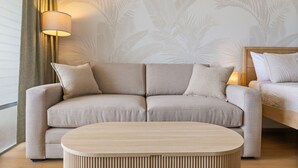 A modern living room with a beige sofa, a round wooden coffee table, and a lamp. - The Palms: Waikiki studio (Honolulu)