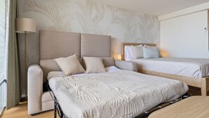 A hotel room with a sofa bed, a single bed, and a nightstand. - The Palms: Waikiki studio (Honolulu)