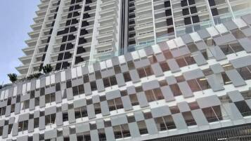 Un edificio de gran altura con un diseño arquitectónico moderno, que presenta una fachada en forma de rejilla y una entrada destacada con señalización.