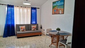 A room with a sofa, a dining table, and a painting on the wall. - CortLang Vacation Rentals Costambar (Puerto Plata)