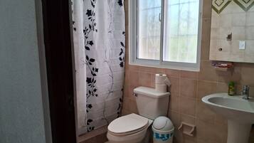 Un bagno con il water, un lavandino e una finestra con tenda.