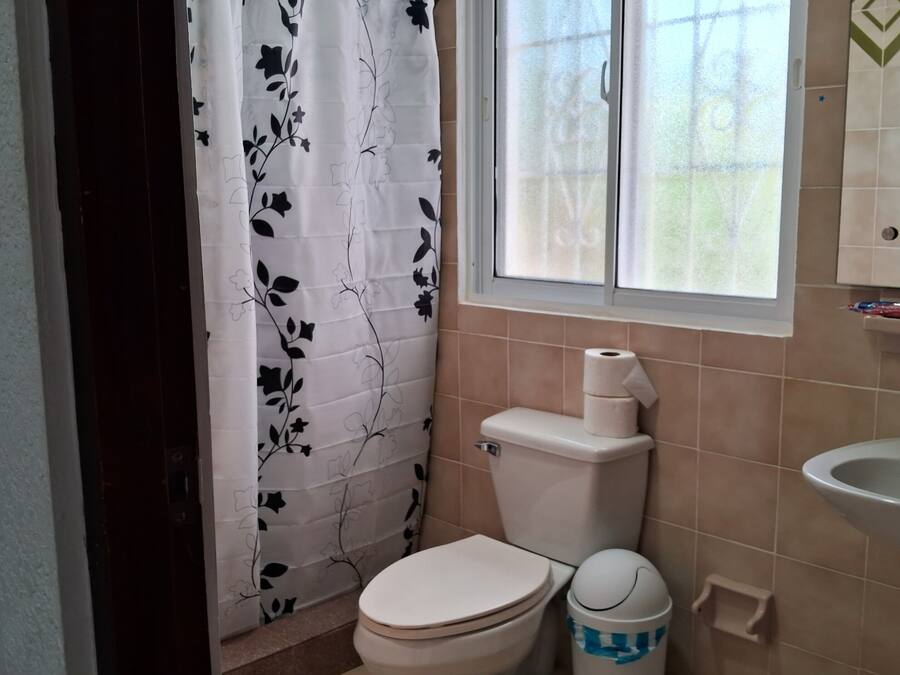 Un bagno con il water, un lavandino e una finestra con tenda.