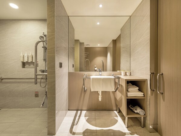 A modern bathroom with a shower, sink, and towel rack.