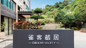 A sign for 'CHECKIN SELECT' hotel with a modern building and a landscaped area with trees and plants. - CHECK inn SELECT - Taipei NeiHu (Taipei)