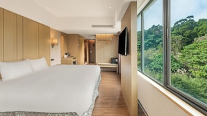 A modern hotel room with a large bed, a desk, a TV, and a view of a forest. - CHECK inn SELECT - Taipei NeiHu (Taipei)