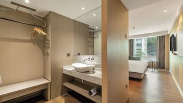 A modern bathroom with a large mirror, a white sink, and a bench.