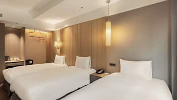 Una habitación de hotel con dos camas, mesitas de noche, una lámpara, un teléfono y un perchero.