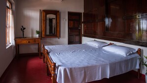 A bedroom with a wooden bed, a wooden dresser, a mirror, and a red floor. - Kuttanad Kayak Club- Riverside Heritage Homestay In Alleppey Backwater village (Alappuzha)