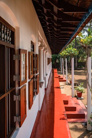Um corredor com paredes brancas, portas de madeira e chão vermelho.