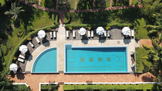 Vue aérienne d’un complexe hôtelier doté d’une grande piscine rectangulaire, de chaises longues et d’un jardin bien entretenu.