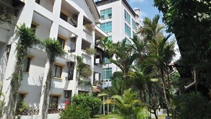 Un hôtel moderne doté de nombreux balcons, d’une végétation luxuriante et offrant une vue sur un ciel d’un bleu éclatant.