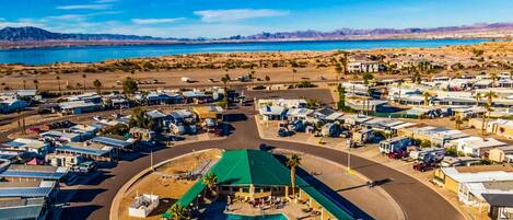 An aerial view of a campground with RVs, a central pool area, and a desert landscape in the background.