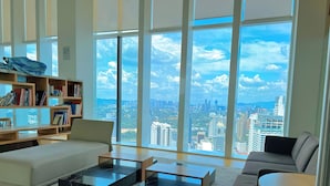 A modern living room with a large window offering a city view. - The Platinum Suites by Emily in Town (Kuala Lumpur)