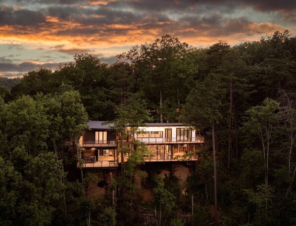 A modern two-story cabin nestled in a forest, with large windows and a balcony. - Skyview Treehouse- luxury with breathtaking views (Sevierville)