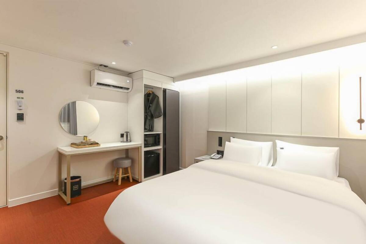Ein Hotelzimmer mit einem Bett, einem Schreibtisch mit Spiegel, einem Kleiderschrank und einem Telefon.