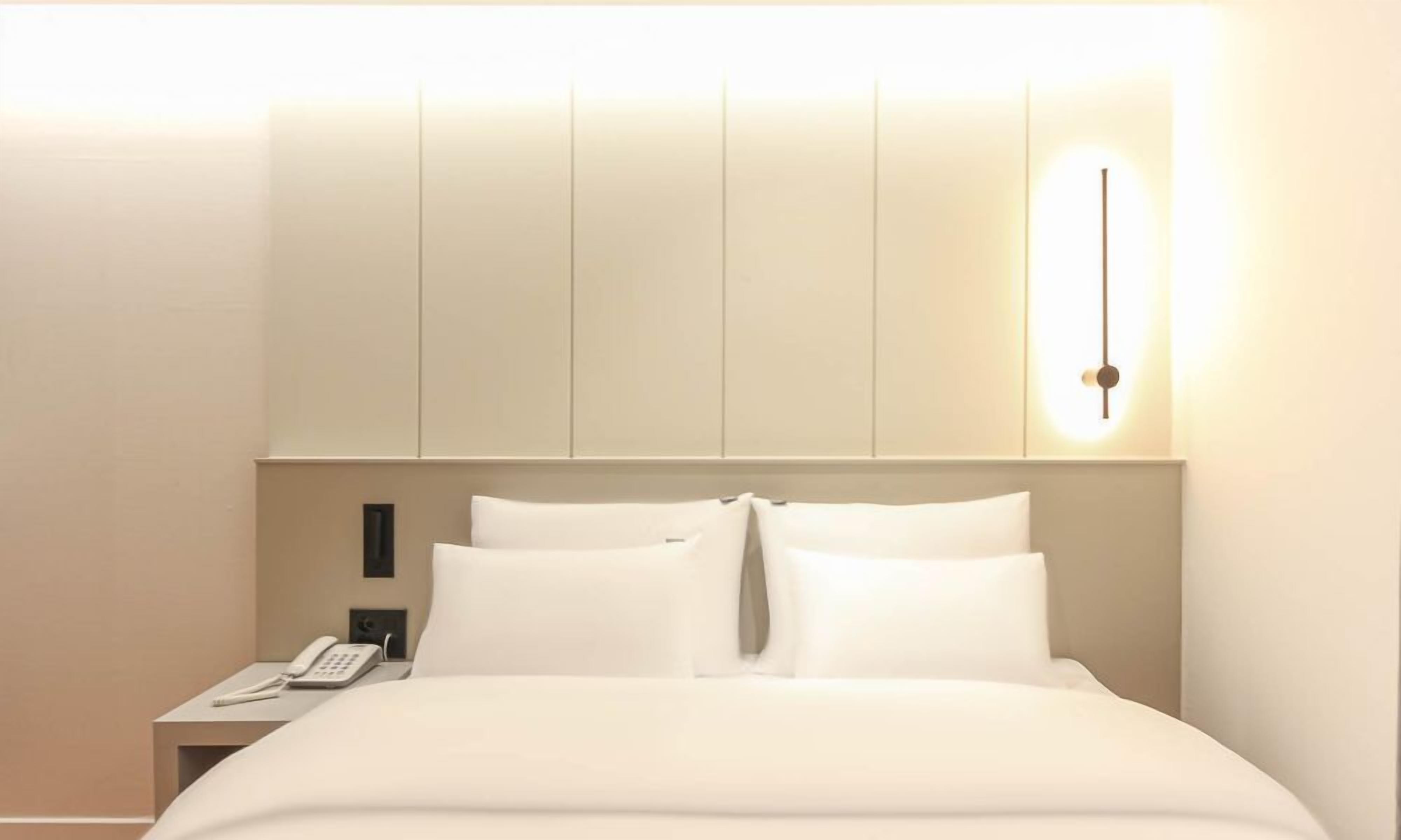 Een hotelkamer met een bed, nachtkastje en een wandlamp.