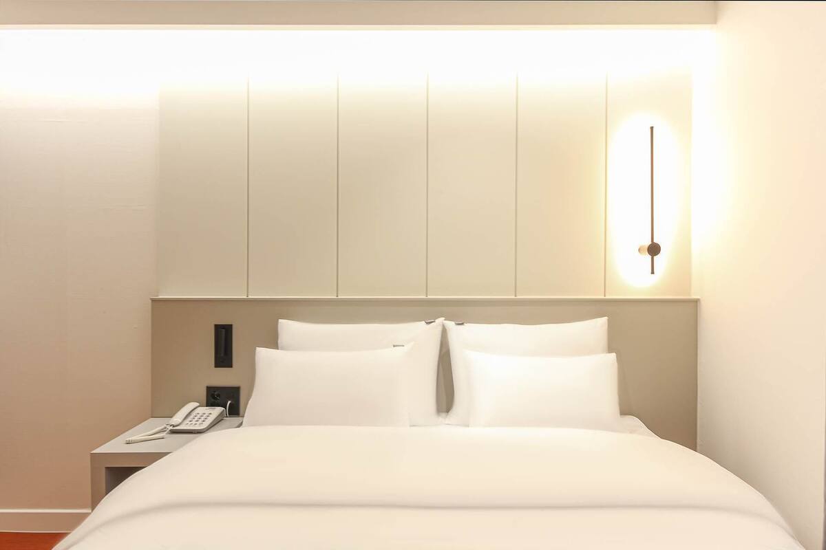 Ein Hotelzimmer mit einem Bett, einem Nachttisch und einer Wandleuchte.