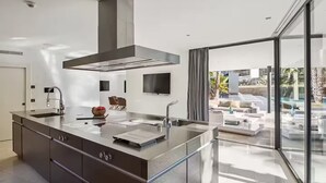 A modern kitchen with a large island, stainless steel appliances, and a view of a pool and outdoor seating area.