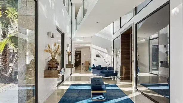 A modern interior with a central seating area, a glass wall, and a view of the outdoors.