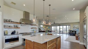 A spacious kitchen with a large island, wooden cabinetry, and modern pendant lighting.