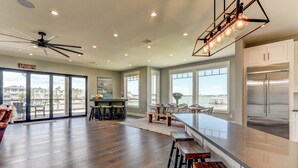 A spacious kitchen with a large island, a dining area with a view, and a ceiling fan.