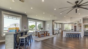 A spacious kitchen with a central island, large windows, and a view of the outdoors.