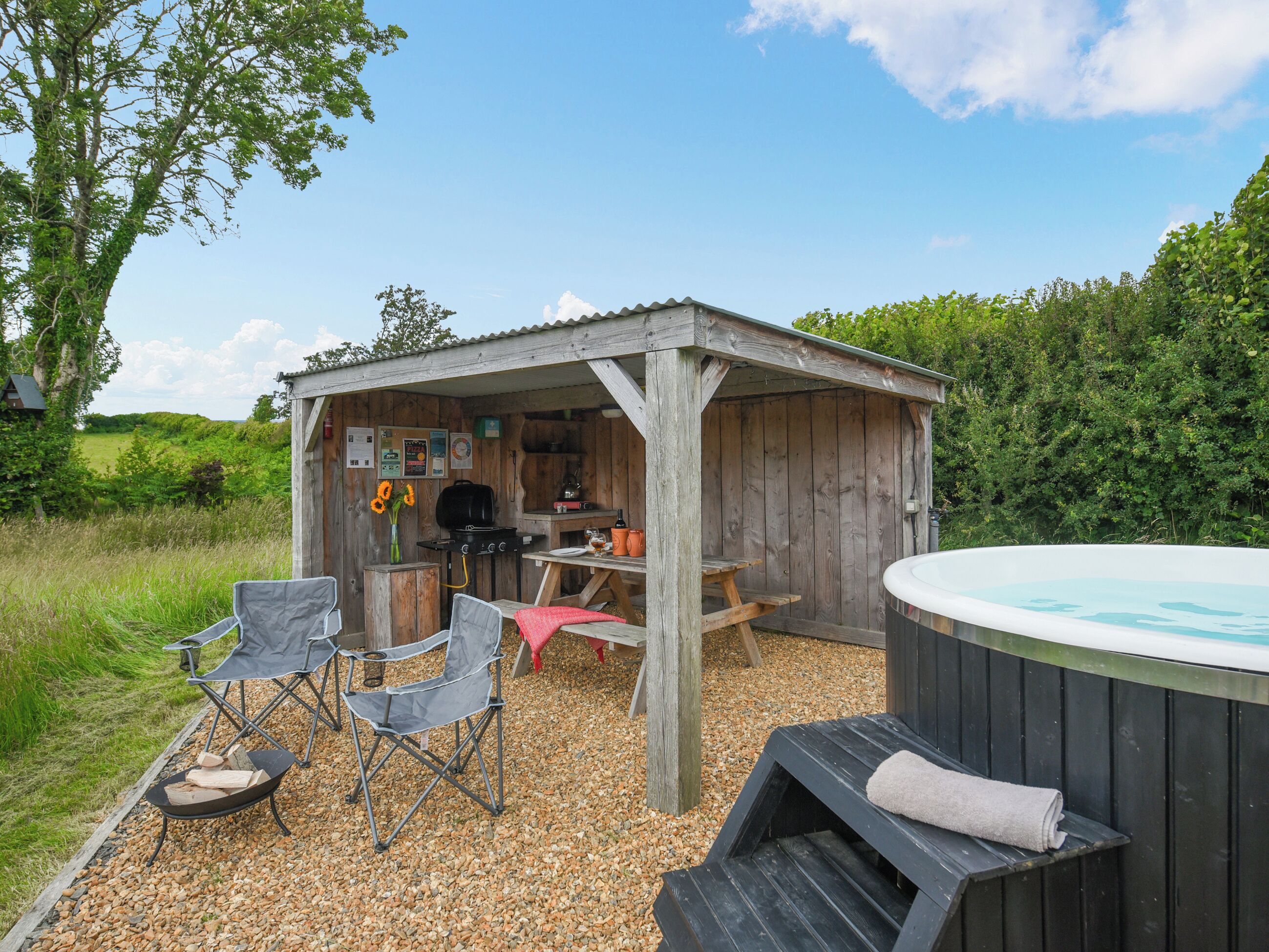 Eine hölzerne Außenanlage mit Whirlpool, Grill und Sitzgelegenheiten.