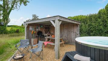 Eine hölzerne Außenanlage mit Whirlpool, Grill und Sitzgelegenheiten.