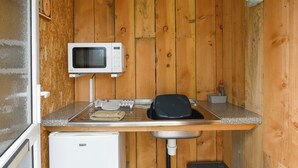 A compact kitchenette with a microwave, a small refrigerator, a sink, and a countertop. - The Hedgehog Pod - UK50067 (Welshpool)