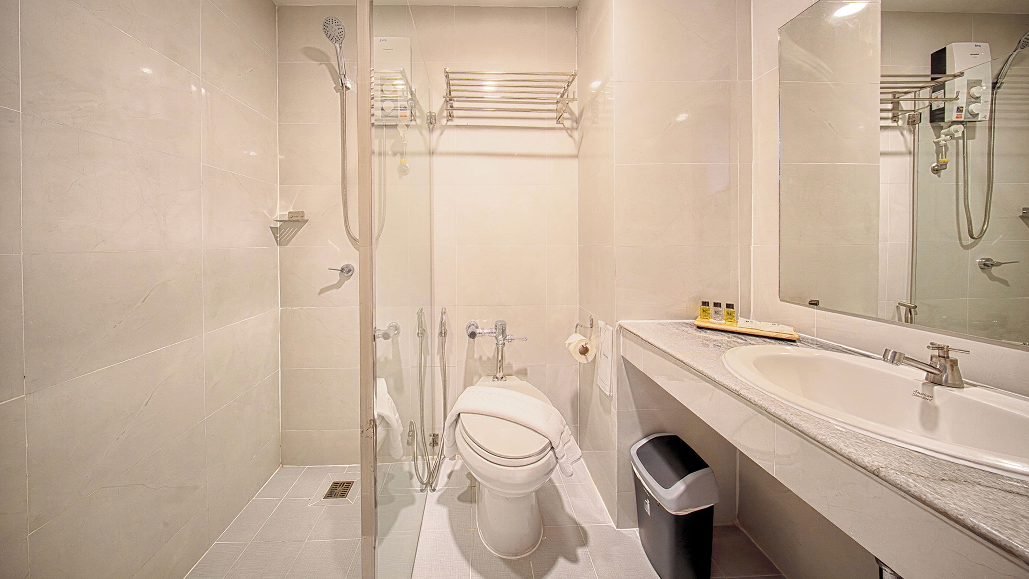 A modern bathroom with a glass-enclosed shower, a toilet, a sink, and a large mirror.