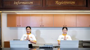 A reception desk with two staff members in uniforms, wooden cabinets above labeled "Information" and "Registration", and a printer on the desk. - B2 Sisaket Boutique & Budget Hotel (Sisaket)