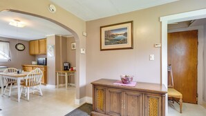 A dining area with a wooden table and chairs, a kitchen with cabinets and appliances, and a framed picture on the wall. - Pet-Friendly Smithmill Retreat w/ Yard! (Smithmill)