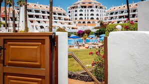 Un resort con varias edificaciones blancas, una piscina y palmeras.