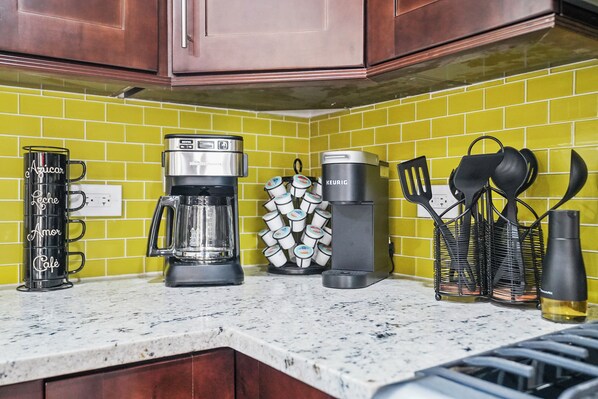 Una encimera de cocina con una cafetera, una jarra de café y un soporte para tazas.