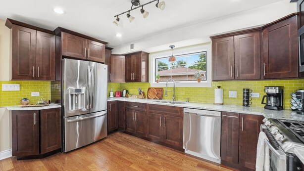 Una cocina moderna con armarios de madera oscura, electrodomésticos de acero inoxidable y un salpicadero verde.