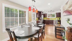Una cocina moderna con comedor, que incluye una mesa redonda grande, sillas de madera e iluminación colgante.