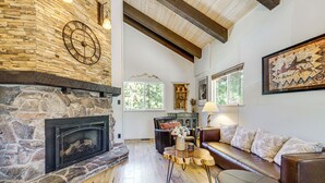 Ein Kamin aus Stein, ein Holzboden, ein Ledersofa und ein Gemälde an der Wand.