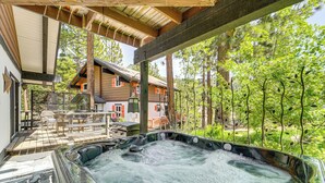 Ein Whirlpoolbereich mit Holzterrasse, überdachter Sitzgelegenheit und einem Haus im Hintergrund.