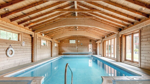 Una piscina interior con paredes de madera y un techo alto.