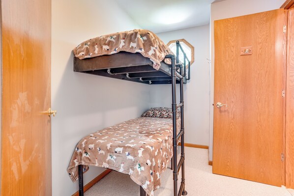Ein Stockbett mit gemustertem Bettbezug, eine Holztür und ein kleines Fenster.