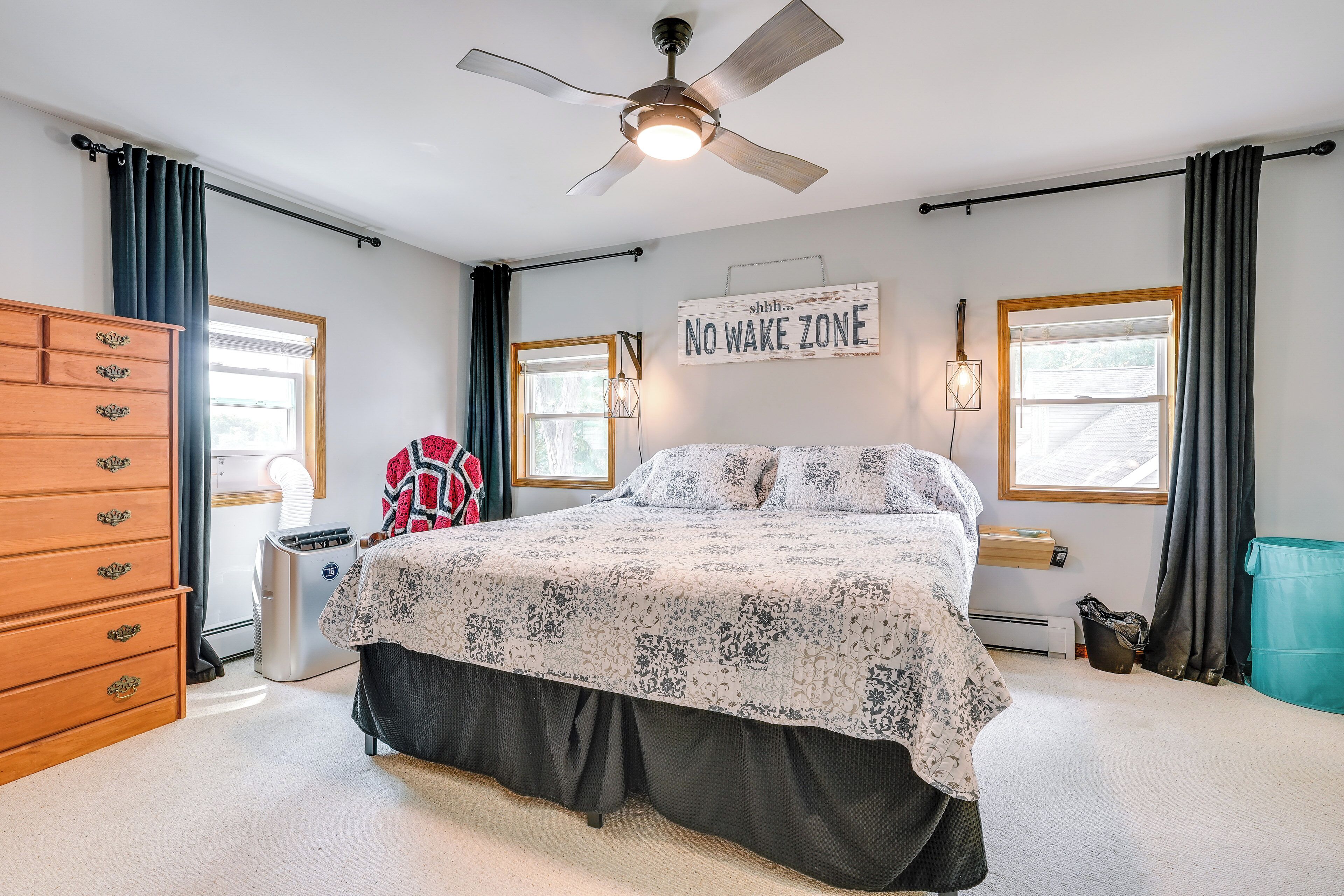 A bedroom with a bed, a dresser, a heater, and a 'No Wake Zone' sign.
