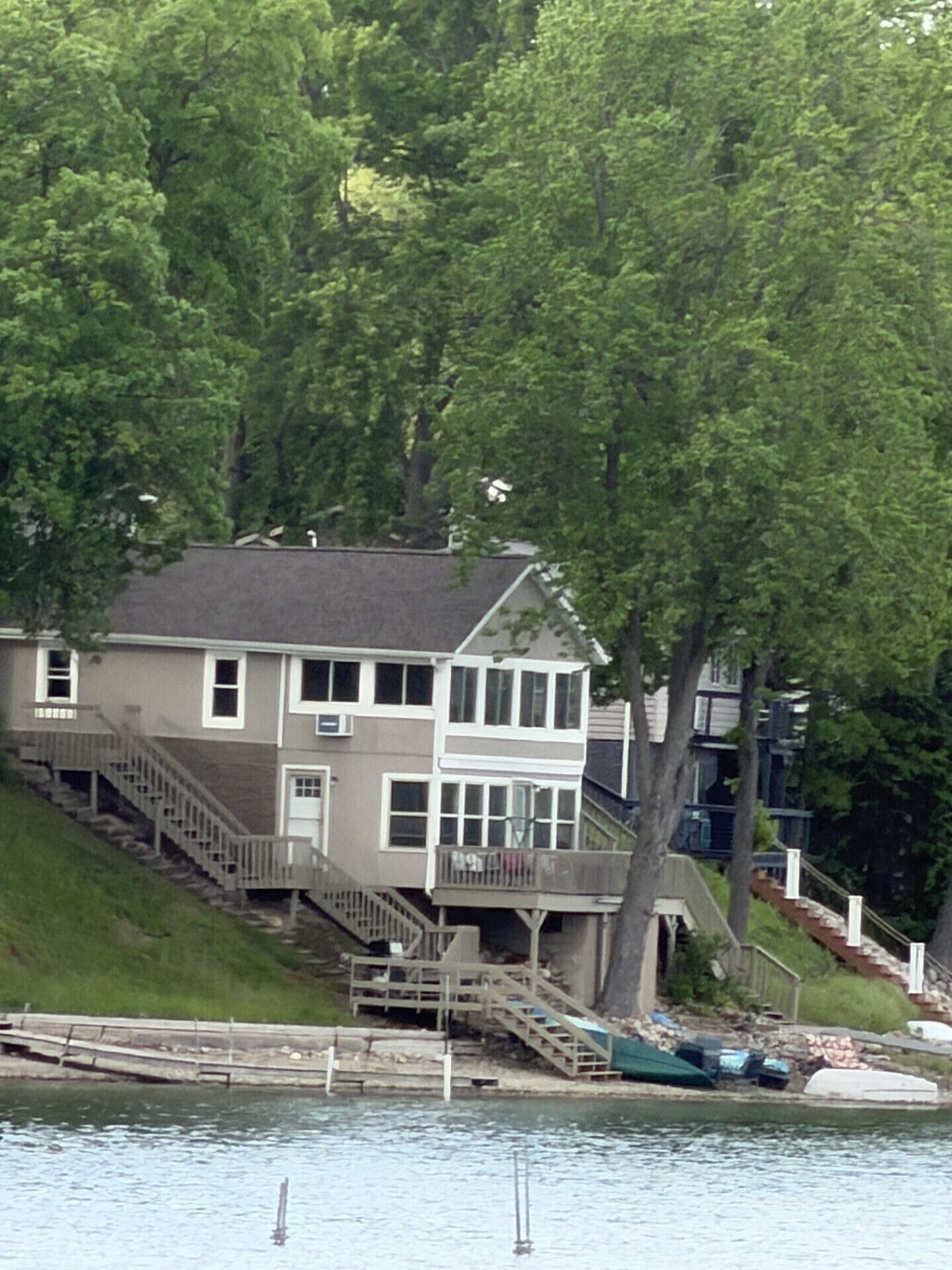 A two-story house with a balcony, a staircase, and a dock extending into a body of water.