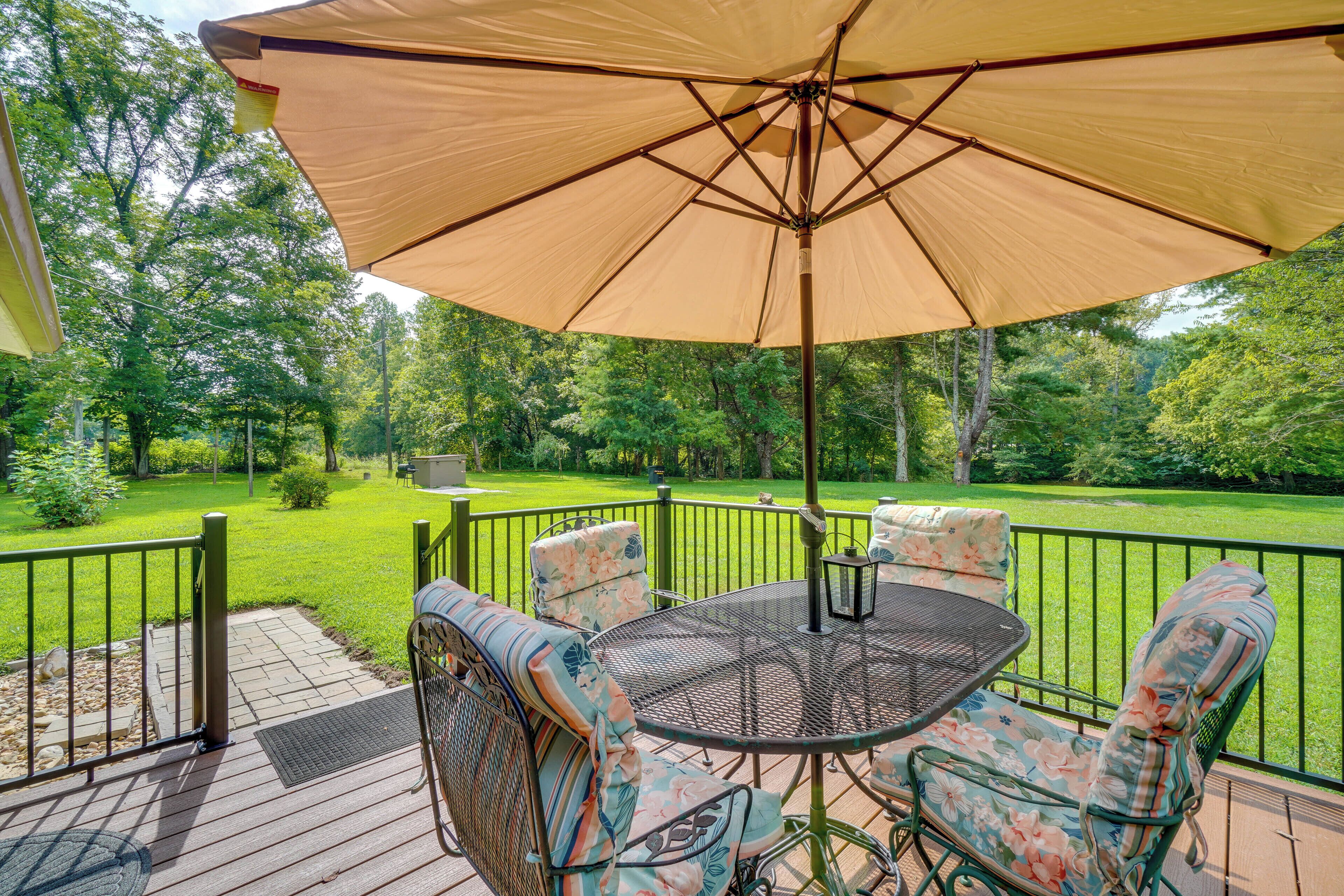 A deck with outdoor furniture, a table, and a large umbrella.