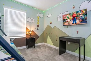 Una habitación infantil con cama, escritorio, lámpara y televisor.