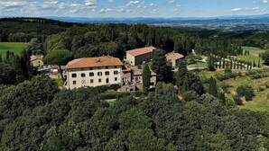 A large estate with multiple buildings surrounded by dense forests and rolling hills.