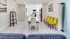 A modern kitchen with white cabinets, a stainless steel refrigerator, and a dining area with a white table and chairs. - 5 Mi to Beach: Group Getaway w/ Yard in Miami (Miami)